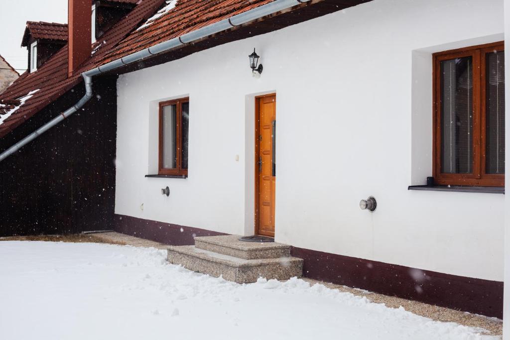 una casa blanca con una puerta en la nieve en Gazdova chalupa, en Vavrišovo