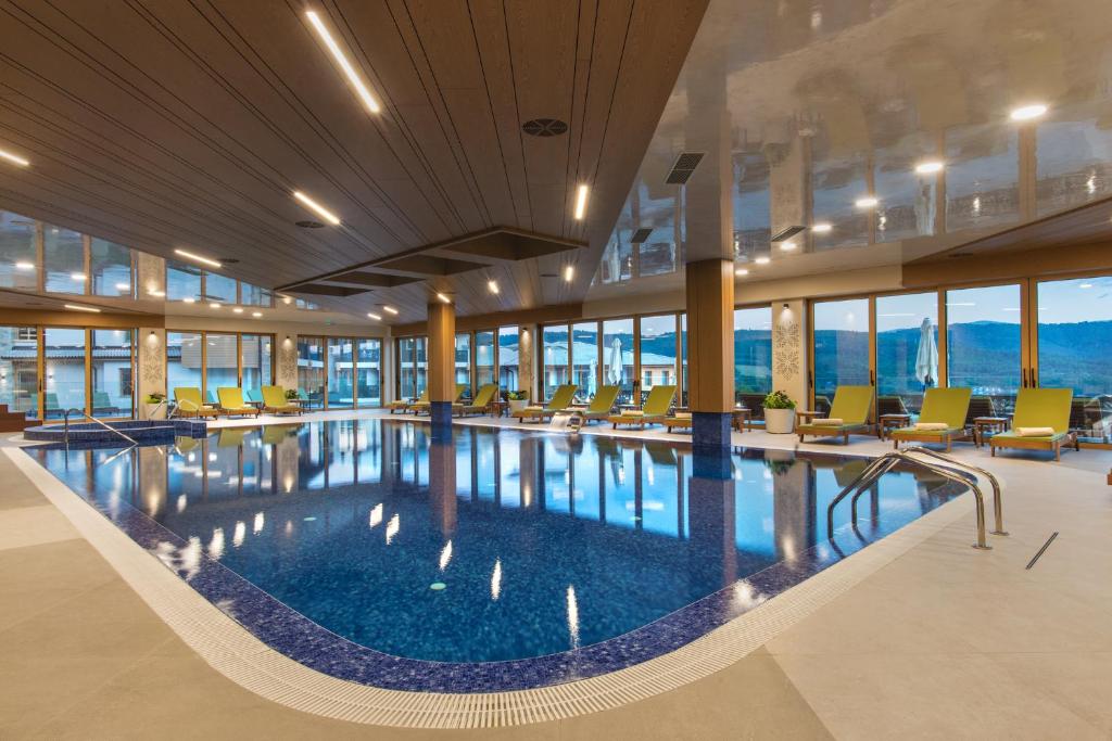 a large swimming pool in a hotel lobby with chairs at Wine & SPA Hotel Chukara in Tryavna