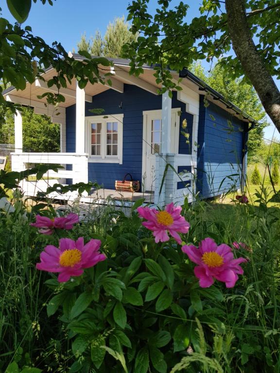 une maison bleue avec des fleurs roses devant elle dans l'établissement Campsite 37A - Wooden Cabins, à Karklė