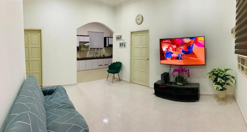 sala de estar con sofá y TV en la pared en Nurul Amin Guest House Pantai Cahaya Bulan Kota Bharu en Kota Bharu