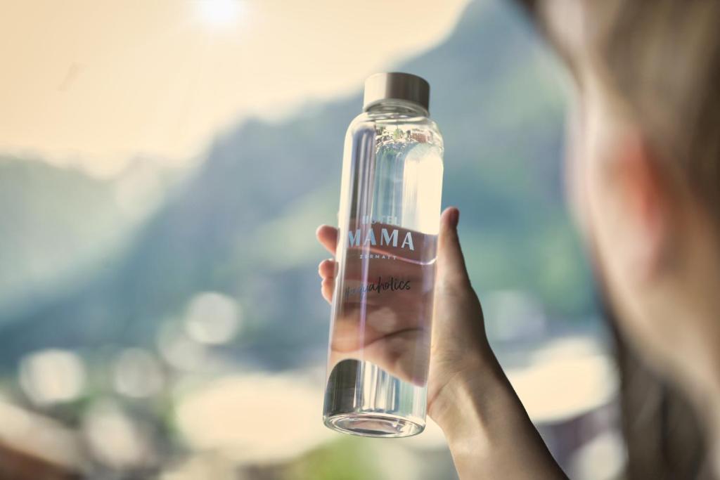 a person is holding a bottle of water at Hotel ZERMAMA Zermatt in Zermatt