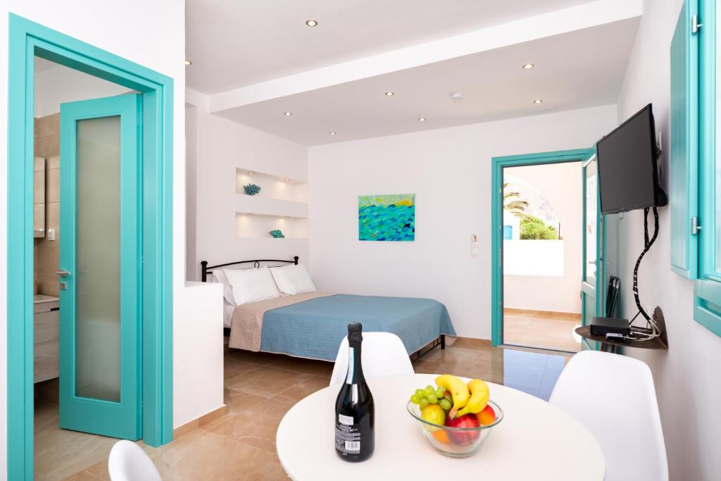 Habitación con cama y mesa con un bol de fruta en Dona Beach Resort, en Perissa