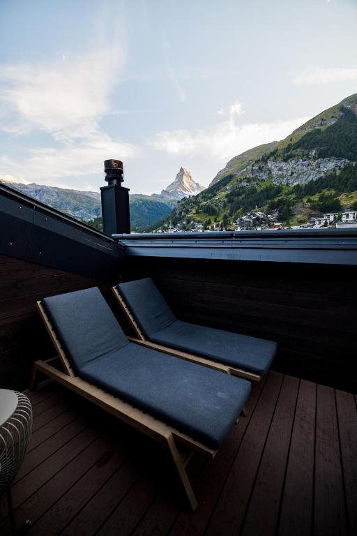 a chair on a deck with a view of a mountain at Hotel ZERMAMA Zermatt in Zermatt