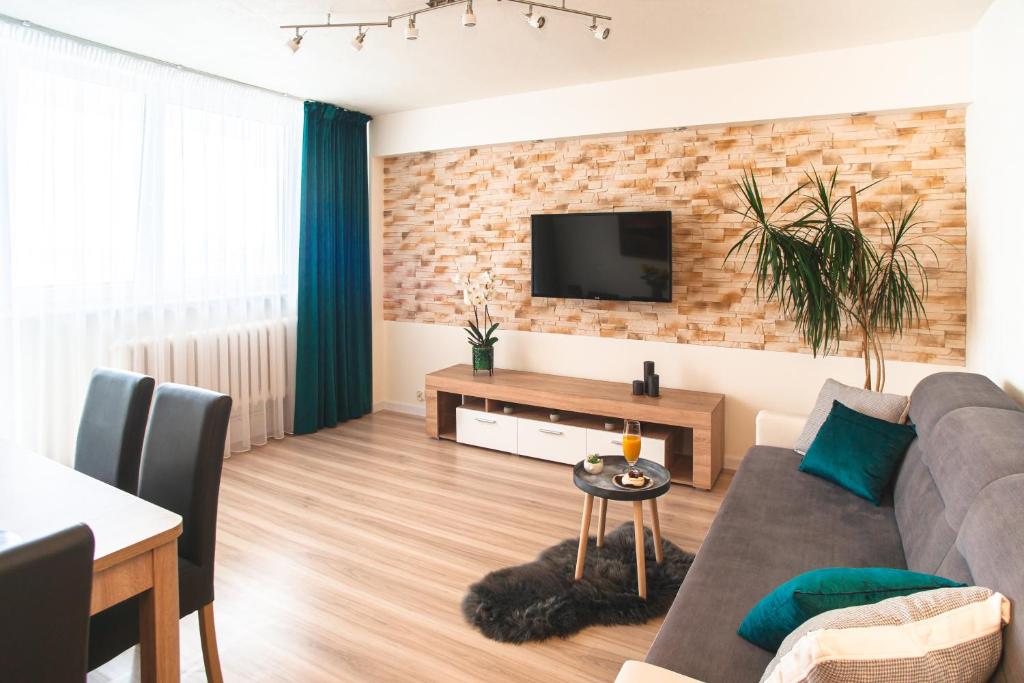 salon z kanapą i telewizorem na murze z cegły w obiekcie Apartament Panorama w Warszawie