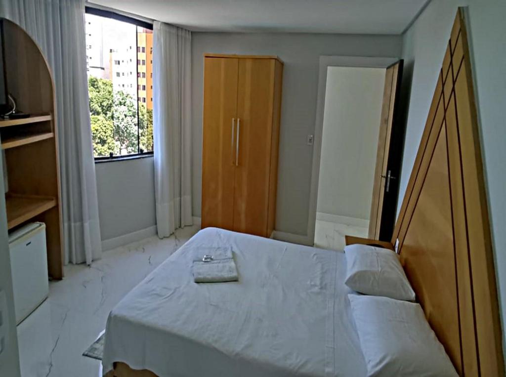 Schlafzimmer mit einem großen Bett mit einem Kopfteil aus Holz in der Unterkunft Horto Executivo Hotel in Ipatinga