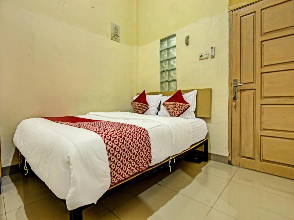 a bedroom with a large bed with red and white pillows at OYO Life 91268 Homestay Bu Erma Syariah in Talang Kelapa