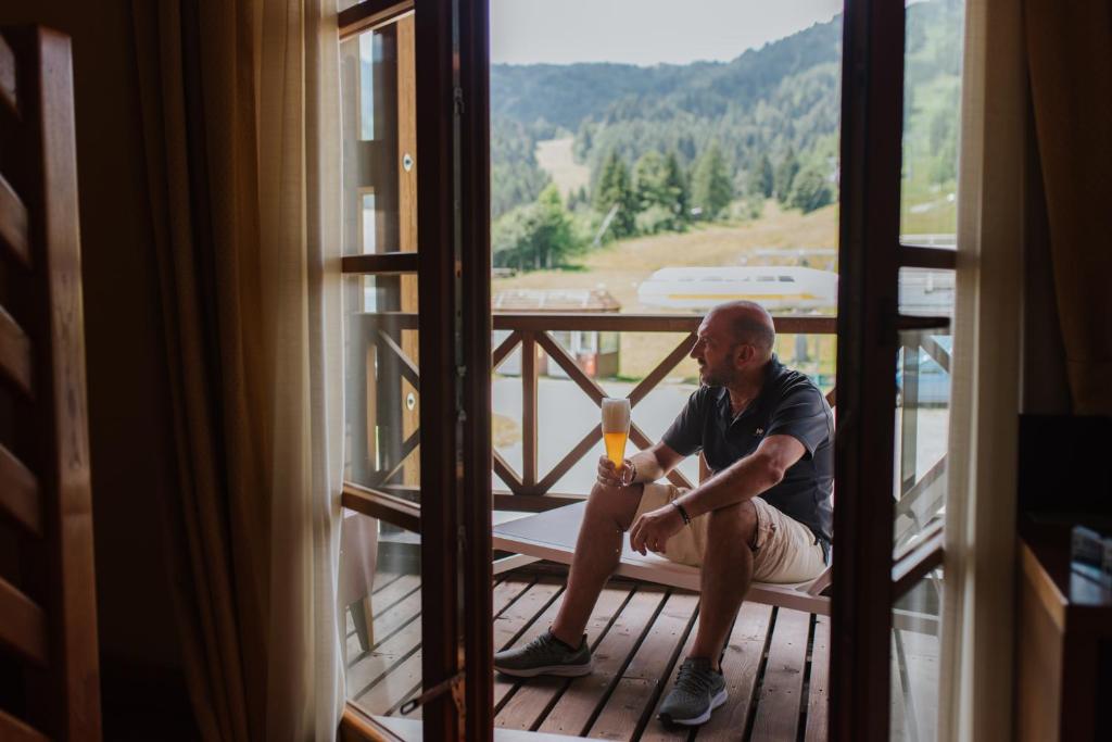 a man sitting on a window frame holding a hammer at Hotel Enzo Moro in Sùtrio