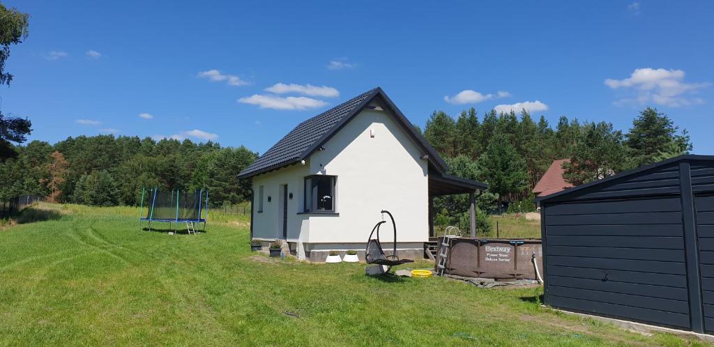 a small white house with a black roof in a field at Wierzchy 34 in Wierzchy