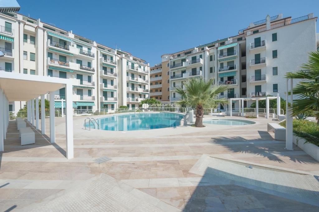 una piscina frente a algunos edificios de apartamentos en Residence El Palmar Immobiliare Pacella, en Lido di Jesolo