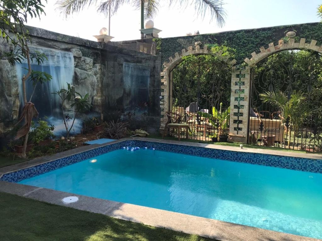 a swimming pool in a yard with a stone wall at Trio Villa with coverable private pool in compound near Mall of Egypt in Sheikh Zayed