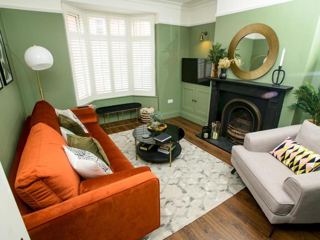 a living room with an orange couch and a fireplace at Pass the Keys Beautiful 3Bed Home with parking in Cathedral Quarter in Lincoln