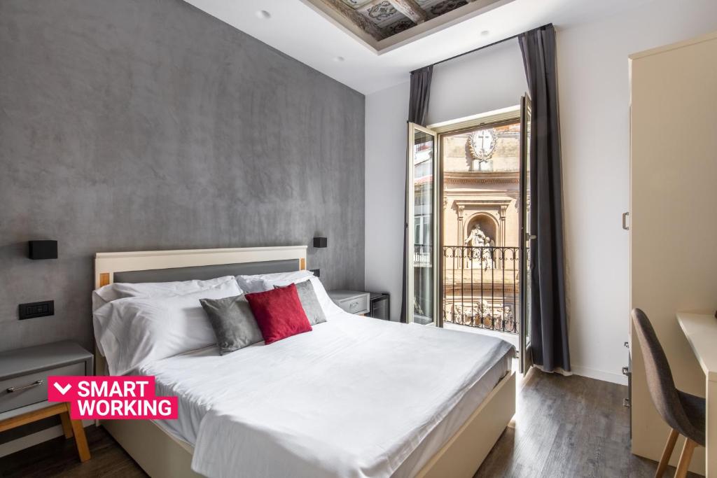 a bedroom with a bed with white sheets and red pillows at Villena Plaza in Palermo