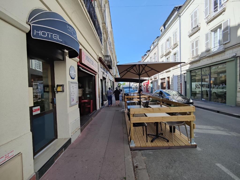 a row of tables on a street next to buildings at Hotel Des Lices - Angers in Angers
