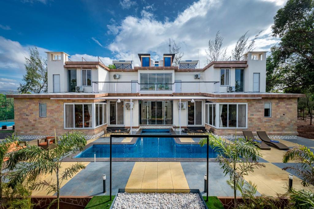 a house with a swimming pool in front of it at SaffronStays Casa De Familia, Karjat - pool villa with ample open space for outdoor games in Jambrung 