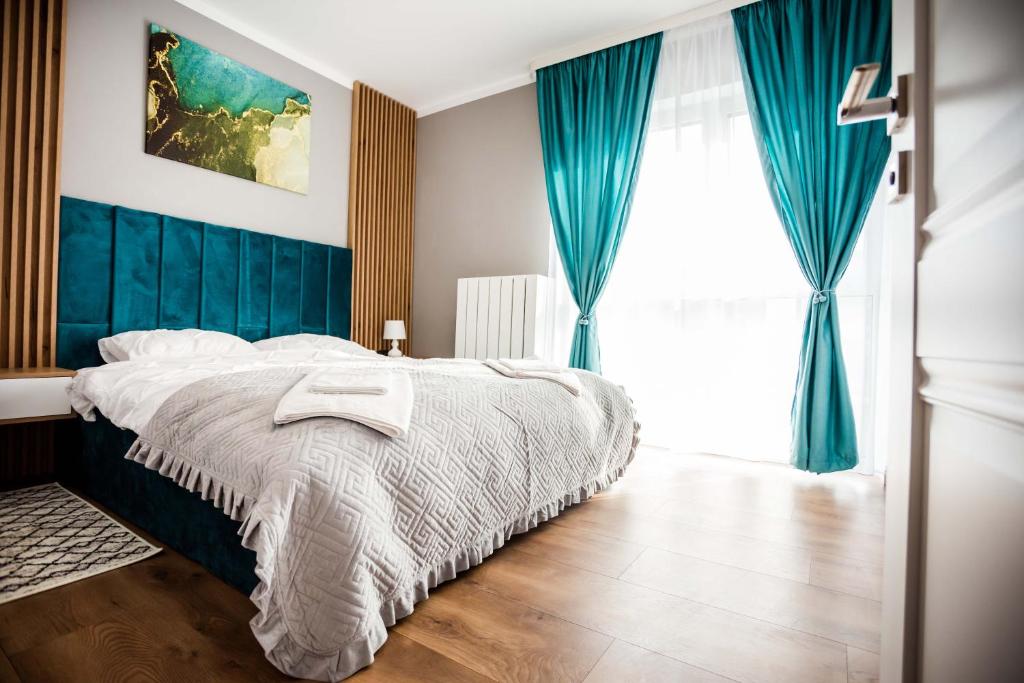 una camera da letto con un grande letto con tende blu di Mon Jardin Apartment a Cluj-Napoca