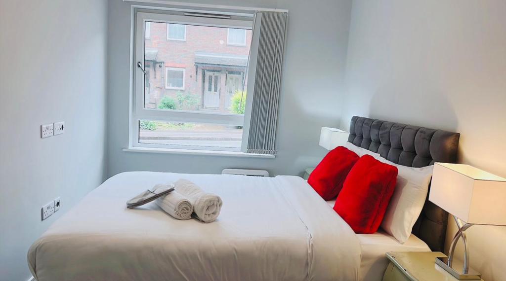 Un dormitorio con una cama con almohadas rojas y una ventana en Mnitri apartment en Luton