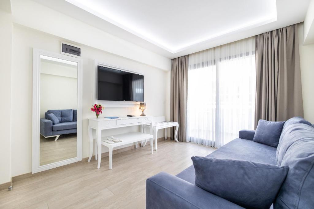 ein Wohnzimmer mit einem blauen Sofa und einem Schreibtisch in der Unterkunft Princess Kinli Suites Hotel in Marmaris