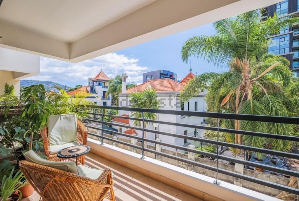 a balcony with chairs and a view of the beach and buildings at Lovely apartment at the best location in Funchal in Funchal