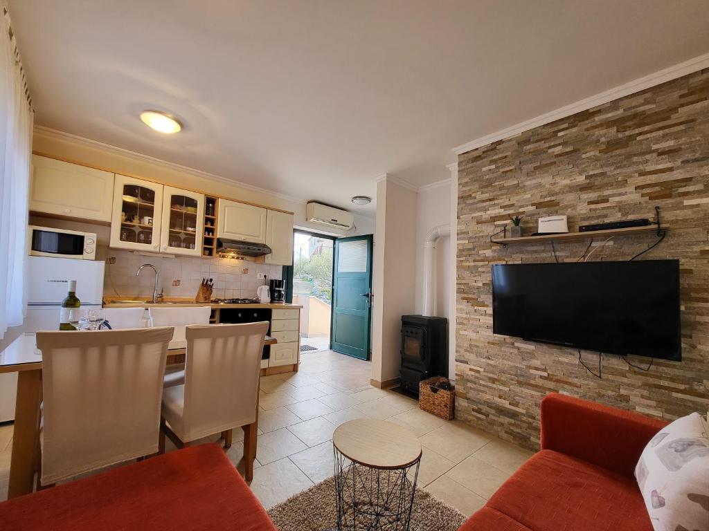 uma cozinha e uma sala de estar com uma televisão numa parede de tijolos em Holiday Home Duje em Iž Mali
