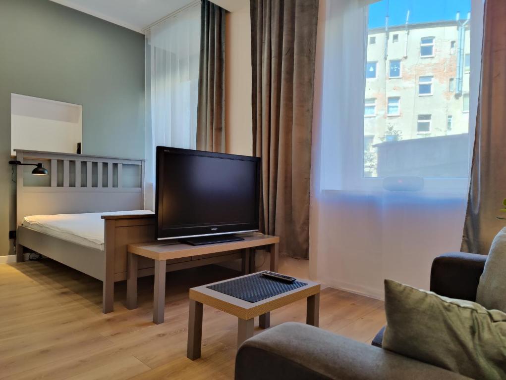 a living room with a television and a bed at Apartament Szczecin in Szczecin