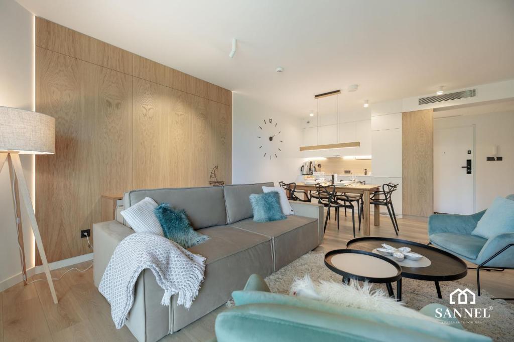 una sala de estar con un sofá y una mesa en Apartament Baltic Blues z dostępem do basenów,strefy saun,jacuzzi - Pinea Apartments Pobierowo - SANNEL Apartments for rent, en Pobierowo