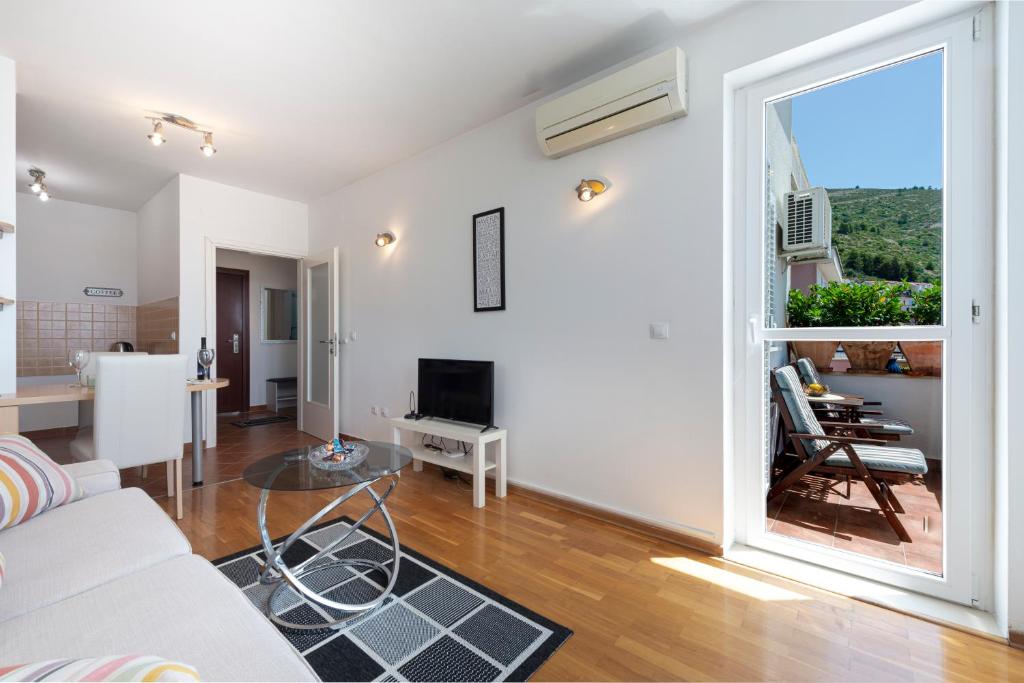 een woonkamer met een witte bank en een groot raam bij Fortuna apartment in Dubrovnik