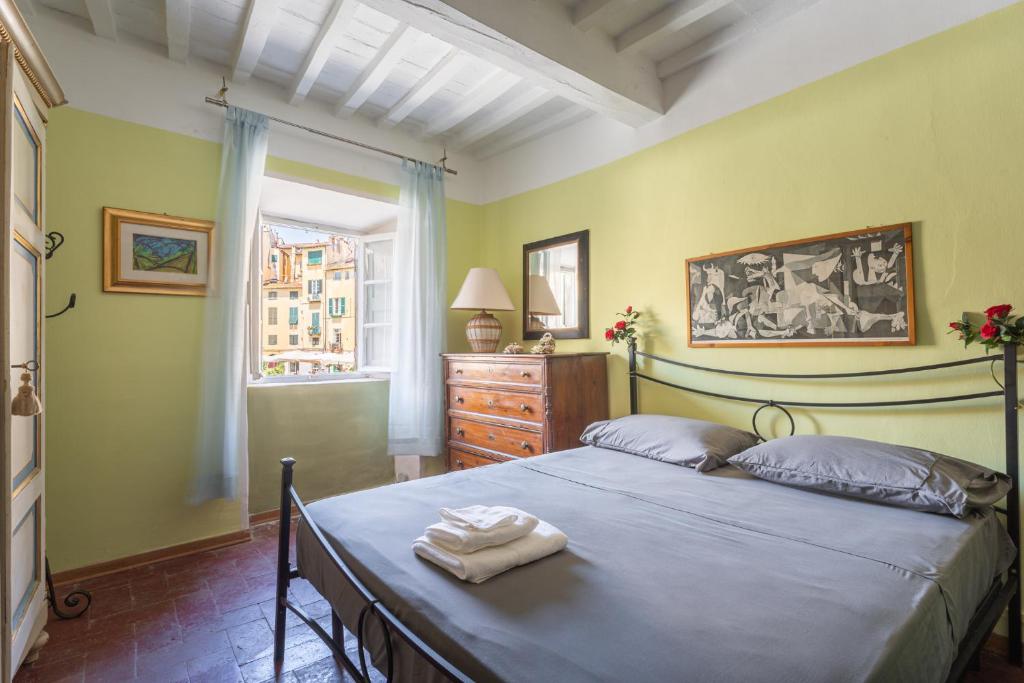 a bedroom with a bed and a dresser and a window at Anfiteatro Lucca in Lucca