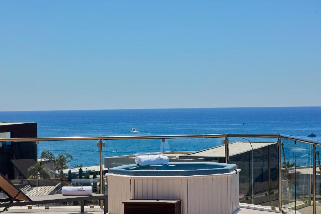 a hot tub on a balcony with the ocean in the background at Atlantica Bay - Adults Only in Limassol