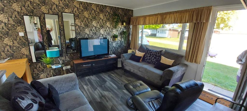 a living room with a couch and a tv at Rosehill Beach in Hemsby