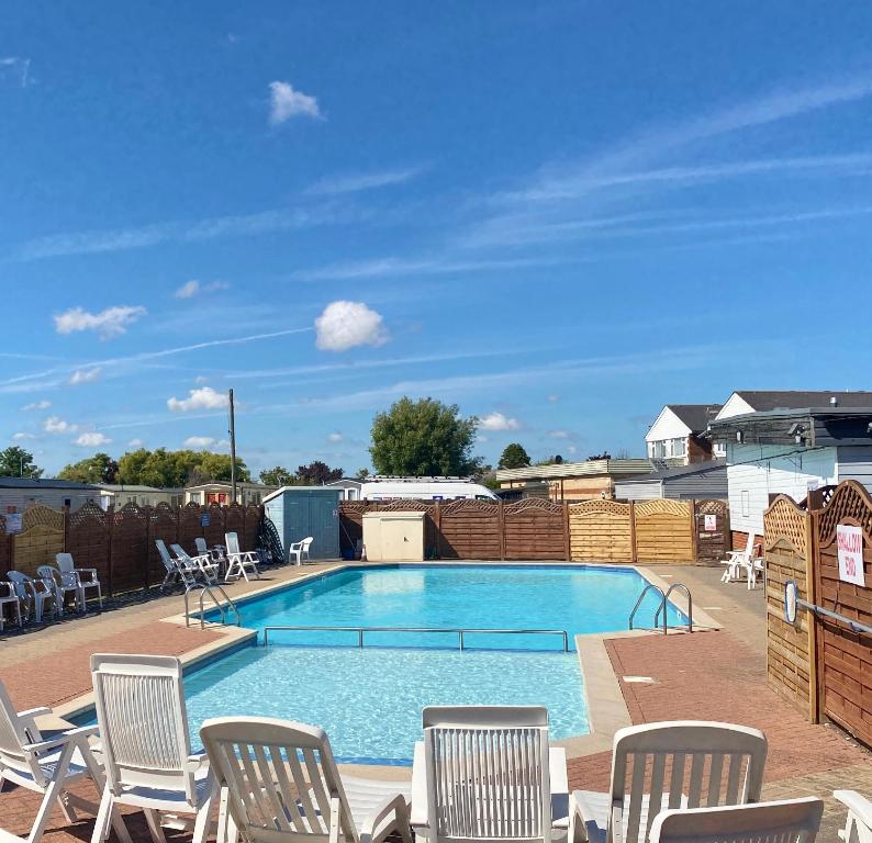a large swimming pool with chairs at Winchelsea Beach Holiday Home - Pool & Beach in Winchelsea