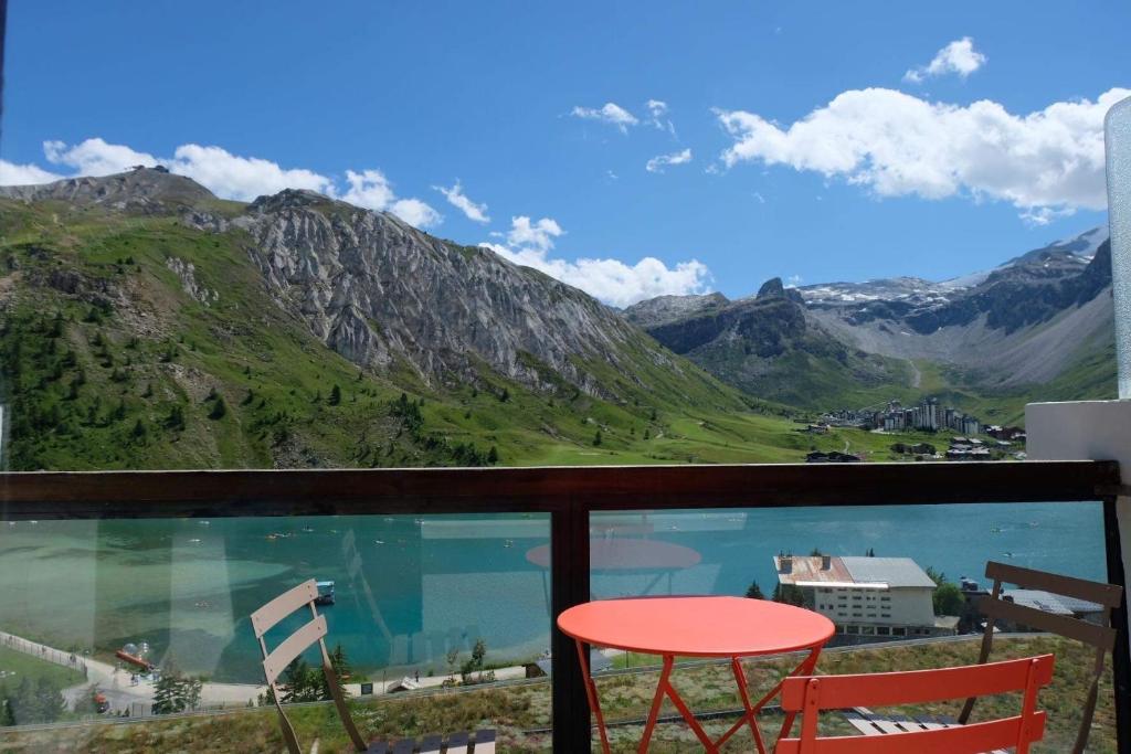 a balcony with a red stool and a view of mountains at Tignes Joli Studio avec vue imprenable sur le lac in Tignes