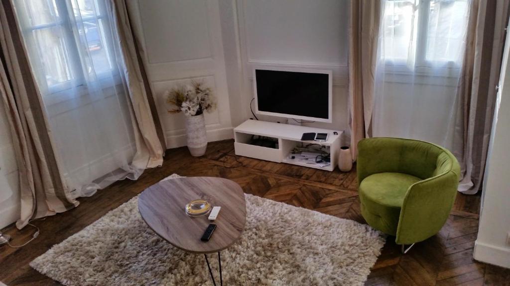 a living room with a television and a table and a chair at A 2 PAS DU PARLEMENT - 55M2 - 2 CHAMBRES in Rennes