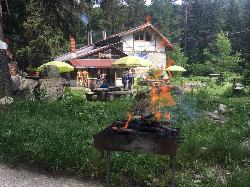 a fire grill in front of a building with umbrellas at Хижа Ловна в Рила in Panichishte