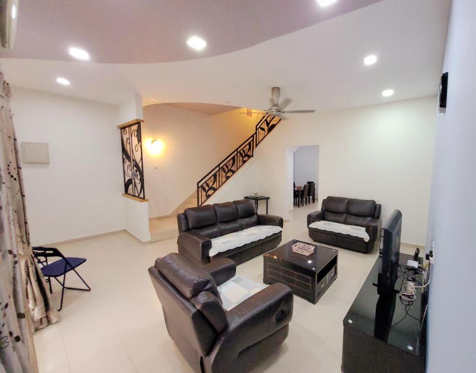 a living room with leather furniture and a staircase at JackBeansprouts Homestay Botani Ipoh in Ipoh