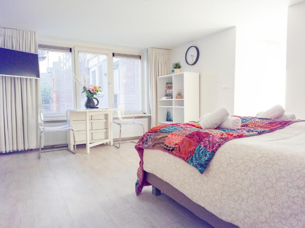 ein Schlafzimmer mit einem Bett und einem Schreibtisch mit einer Uhr in der Unterkunft de Rode Ridder in Zandvoort