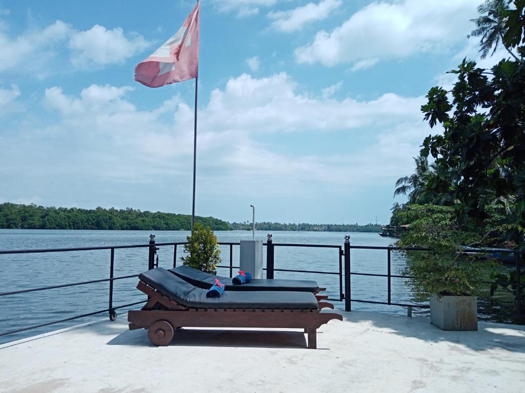 a bench with a flag next to a body of water at Villa Bentota River View in Aluthgama