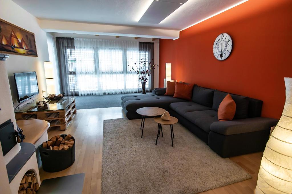 a living room with a couch and a clock on the wall at Apartment ARGENTIS Krumas-Living - Kronplatz in San Vigilio Di Marebbe