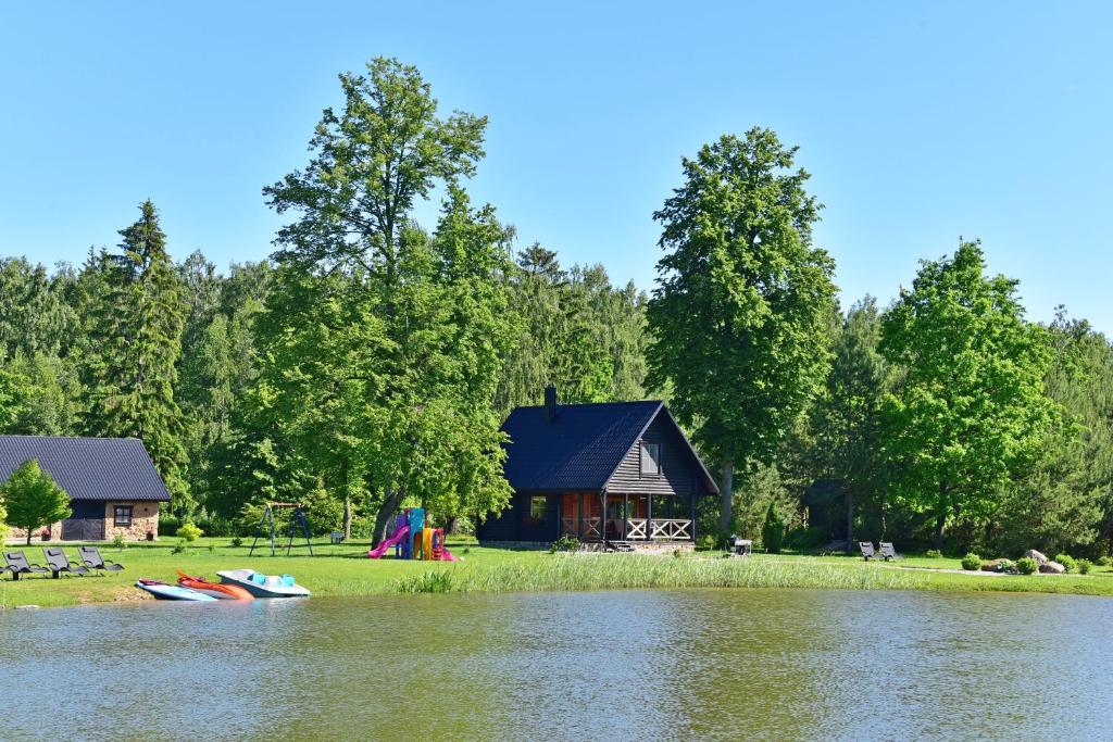 a cabin on the shore of a lake with two boats at Vila Loreta - namelis su pirtimi in Dūdorynė