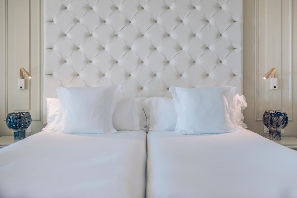 two beds with white sheets and pillows in a bedroom at Iberostar Waves Slavija in Budva