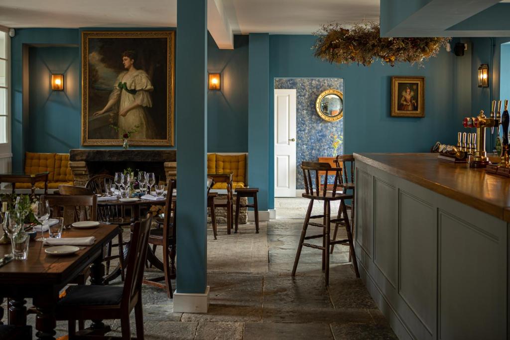 a restaurant with blue walls and a bar with tables at The Queens Arms in Sherborne