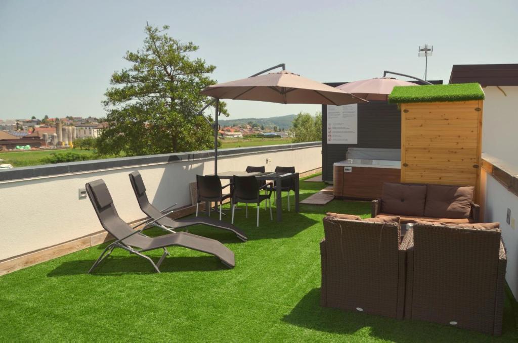 a patio with grass and chairs and an umbrella on a roof at Roof Apartment ART-PE in Trebnje