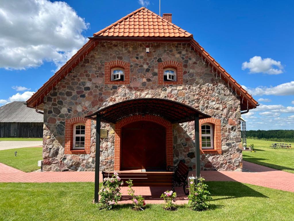 Pakėvio dvaras - Pakevis manor في Kelmė: مبنى حجري صغير مع باب كبير في العشب