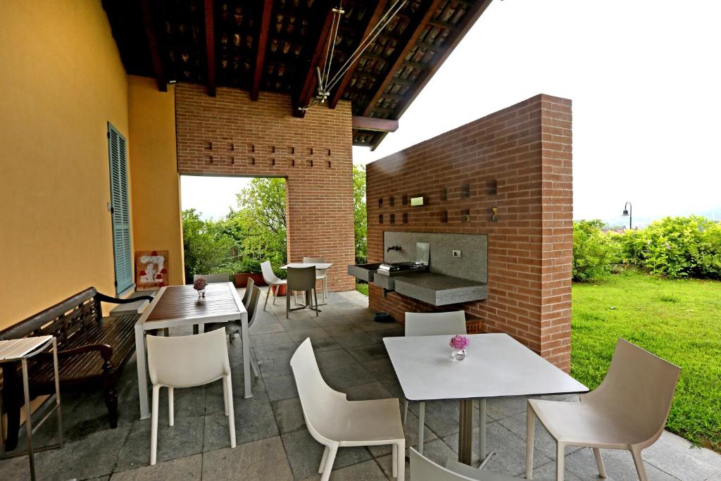 un patio con mesas, sillas y una parrilla en A Casa di Maria, en Grinzane Cavour