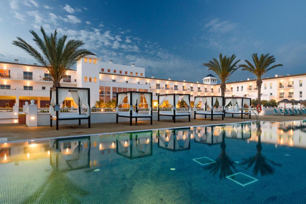 a hotel with a swimming pool in front of a building at Garden Playanatural - Adults Only in El Rompido
