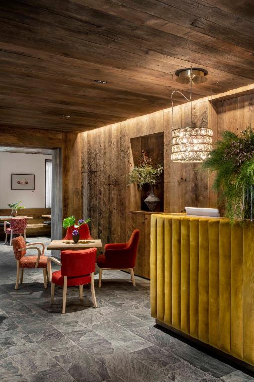 a lobby with red chairs and a table and a dining room at HOTEL de LEN in Cortina dʼAmpezzo