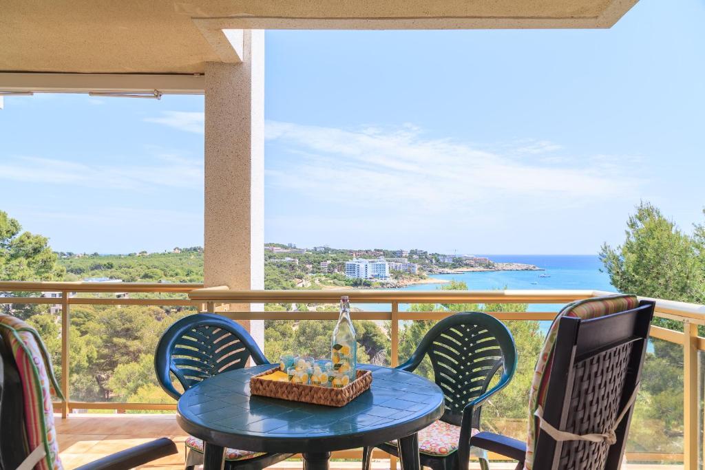 una mesa y sillas en un balcón con vistas al océano en UHC Cala Dorada, en Salou