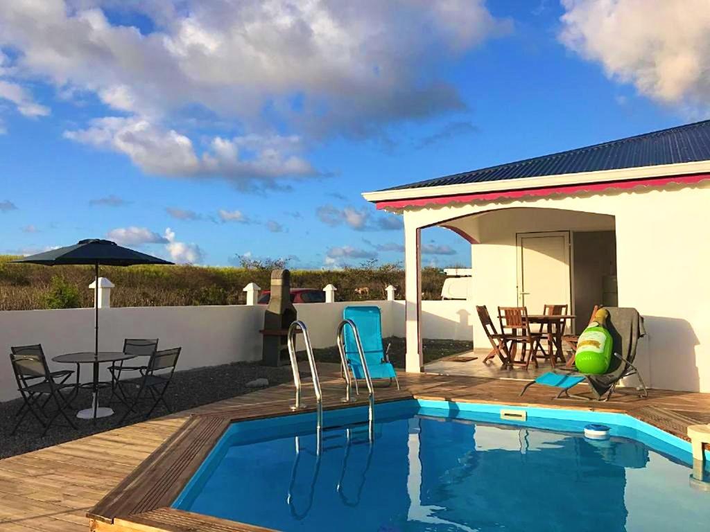 a swimming pool with a patio with a table and chairs at Villa enchanteresse au Moule avec piscine privée in Le Moule