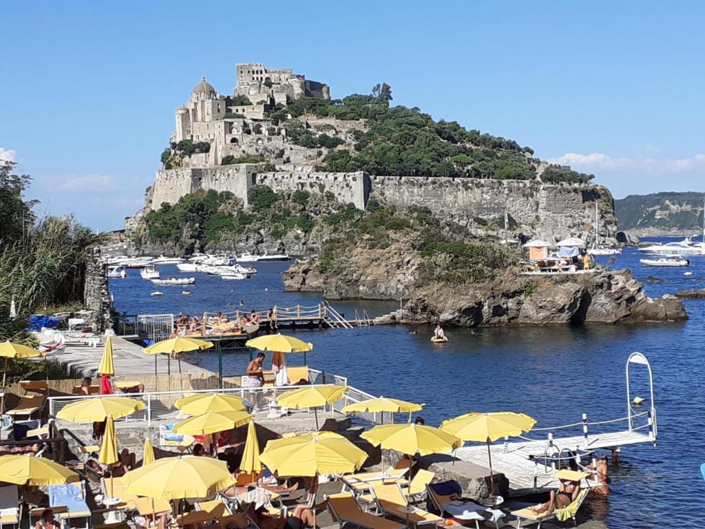 a beach with yellow umbrellas and a castle at Casetta Iacono camera Pithecusa in Ischia