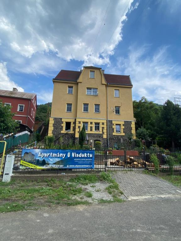 un grande edificio giallo con un cartello di fronte di Apartmány U Viaduktu 46 a Ústí nad Labem