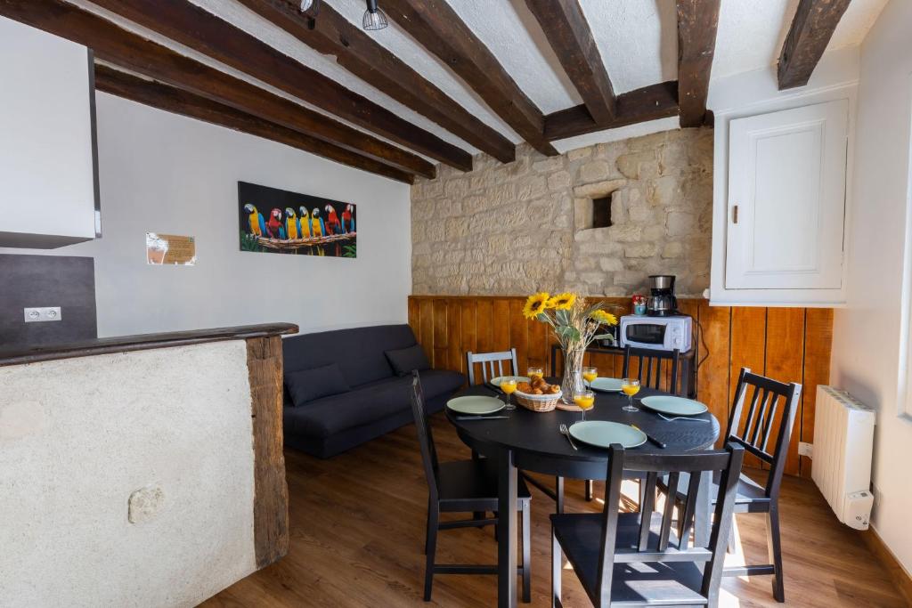 een keuken en een woonkamer met een zwarte tafel en stoelen bij Perruche in Saint-Aignan
